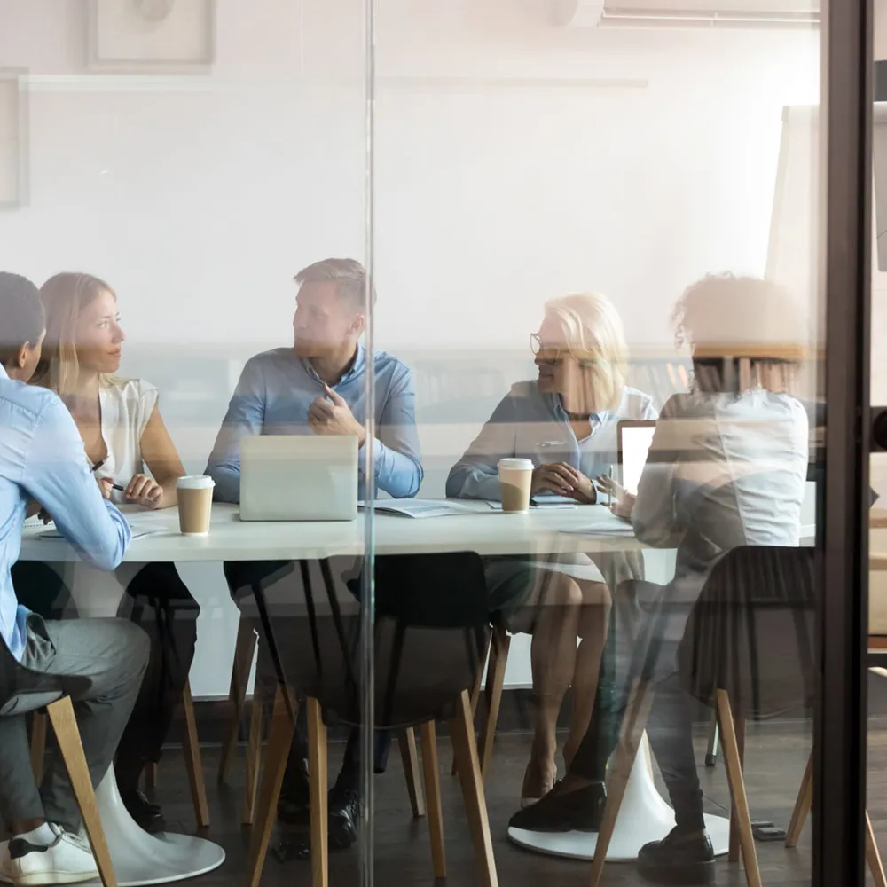 Managementteam overlegt in een vergaderruimte met glazen wand