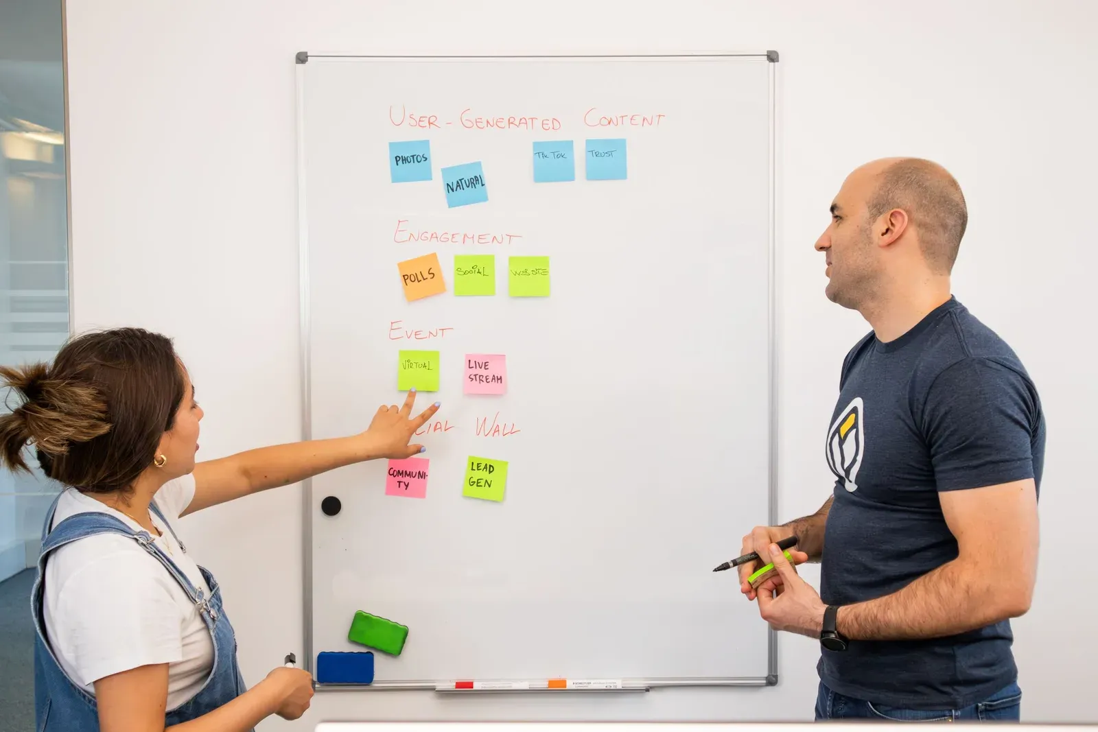 Twee collega's ordenen kpi-categorieën met gekleurde notities op een whiteboard