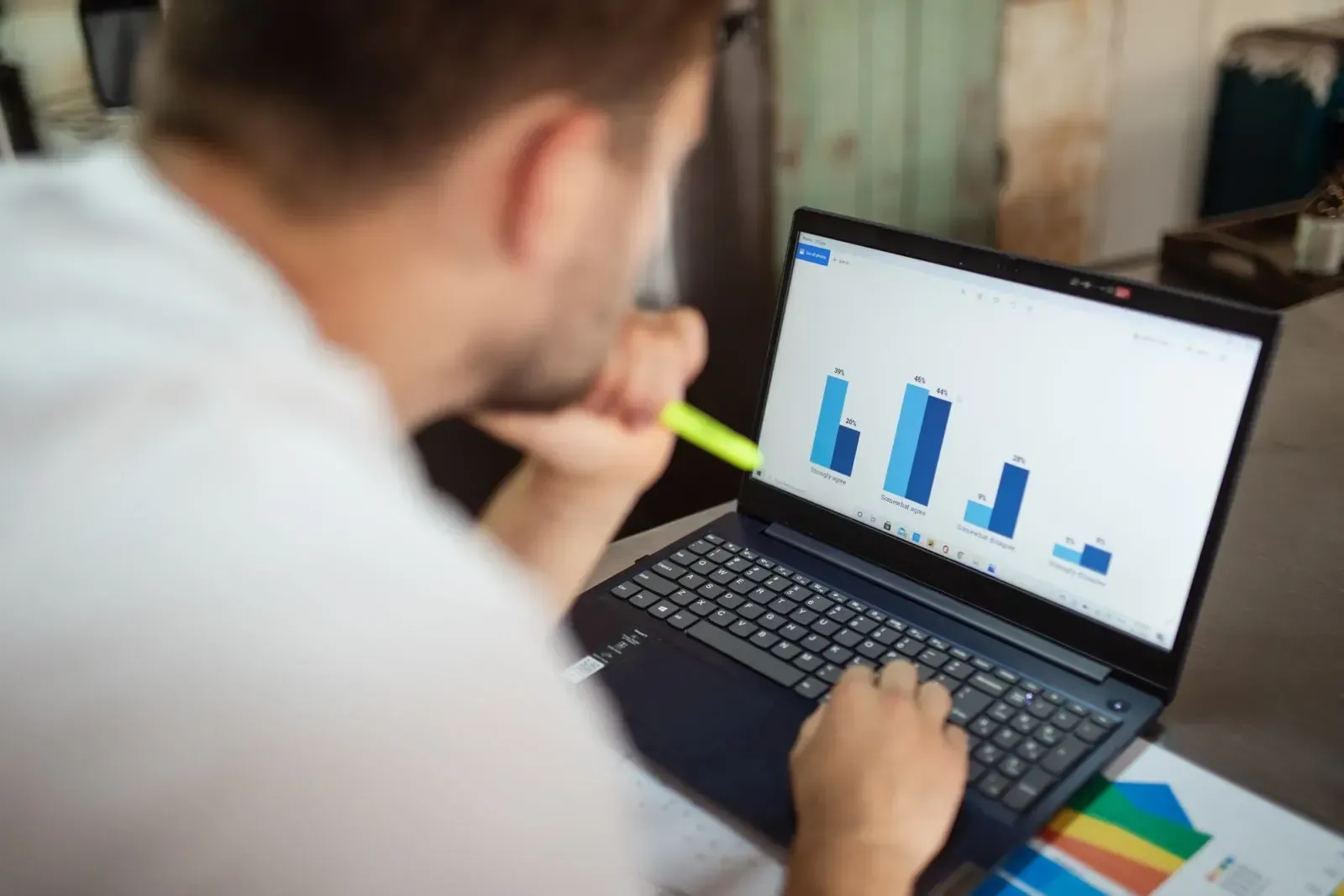 Someone looking at a bar chart on a laptop with a highlighter in hand