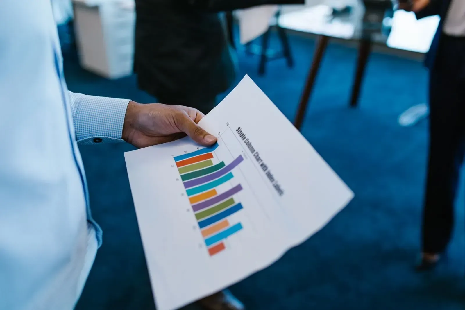 Someone holding a printout of a bar chart in several colours